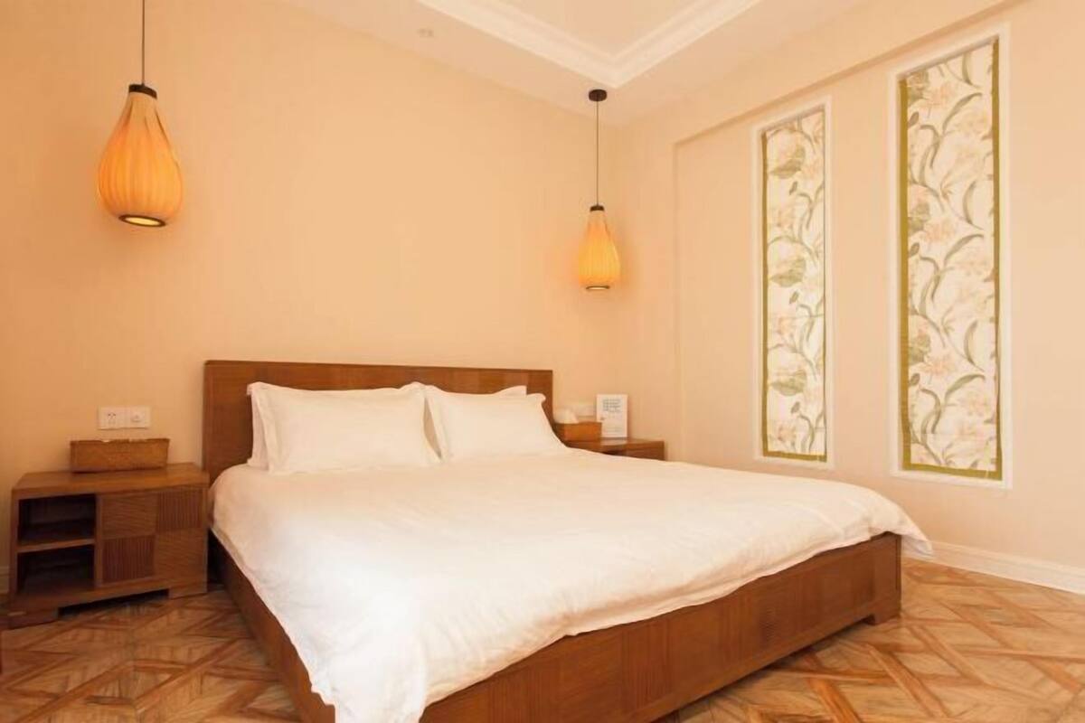 Un dormitorio con una cama de madera, dos mesitas de noche y dos lámparas colgantes.