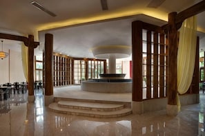 Um hall amplo com uma fonte central, colunas de madeira e área de estar.