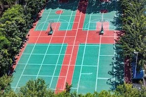 Vista aerea di un campo da basket con due canestri, circondato da alberi.
