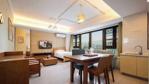 A modern hotel room with a bed, a dining table, a sofa, a TV, and a balcony with a view. - Lingshui Ocean Heart Hotel (Clear Water Bay) (Lingshui)