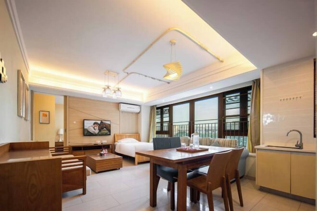 Een moderne hotelkamer met een bed, een eettafel, een bank, een televisie en een balkon met uitzicht.