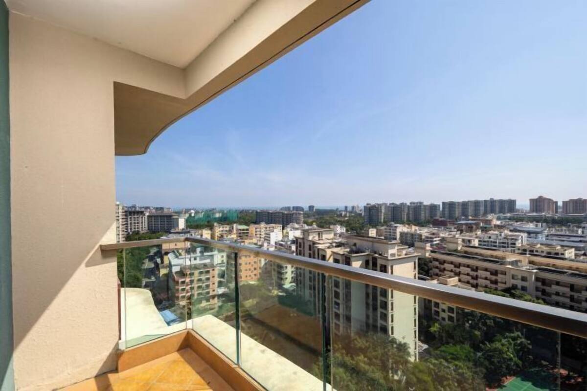 Een balkon met glazen hekwerk met uitzicht op een stadsbeeld.