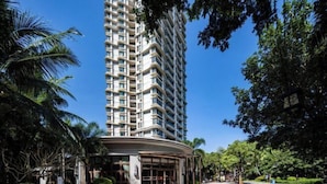 A high-rise hotel with a curved entrance, surrounded by lush greenery and palm trees. - Lingshui Ocean Heart Hotel (Clear Water Bay) (Lingshui)