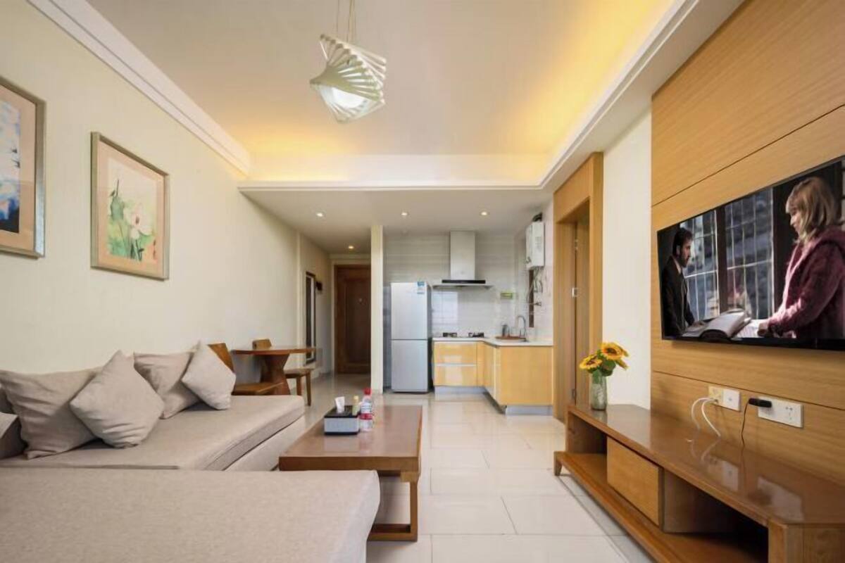 Een moderne woonkamer met een bank, salontafel, televisie en een keuken op de achtergrond.