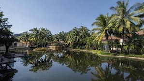 A serene hotel courtyard with a reflective water feature, palm trees, and a clear sky. - Lingshui Ocean Heart Hotel (Clear Water Bay) (Lingshui)