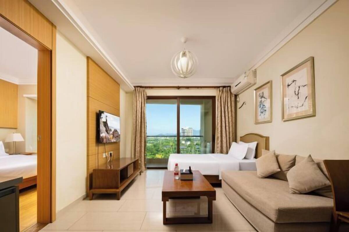 Een hotelkamer met een bed, een bank, een televisie, een salontafel en een balkon met uitzicht.