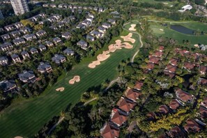 Vista aérea de un barrio residencial con casas, un campo de golf y un edificio grande.