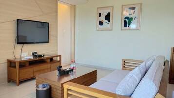 Een moderne woonkamer met een flatscreen televisie, houten meubels en twee abstracte schilderijen aan de muur.