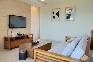 Una sala moderna con un televisor de pantalla plana, muebles de madera y dos cuadros abstractos en la pared.