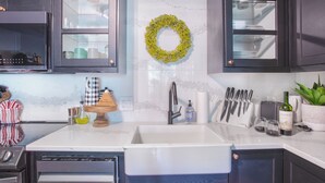 A kitchen with dark cabinets, a white countertop, a stainless steel sink, and a decorative green wreath. - Ski in/Ski out and 1 block from Main Street! (Breckenridge)