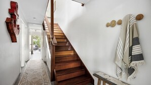 Un escalier en bois dans un couloir, avec un tapis sur le sol.