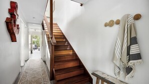 Un escalier en bois dans un couloir, avec un tapis sur le sol.