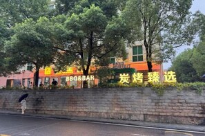 Un restaurante con mesas al aire libre, una pared de piedra y árboles.