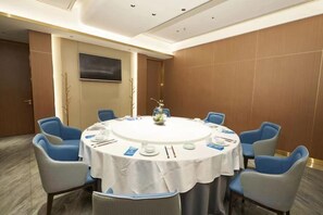 A conference room with a round table, blue chairs, and a white tablecloth. - Mango City Inn (Moon Lake Park North Metro · Window of the World Mango Pavilion) (Changsha)