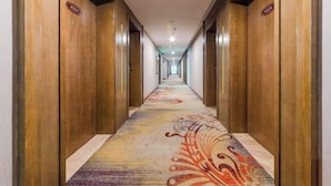 A hotel hallway with wooden doors, a colorful carpet, and a long corridor. - Mango City Inn (Moon Lake Park North Metro · Window of the World Mango Pavilion) (Changsha)