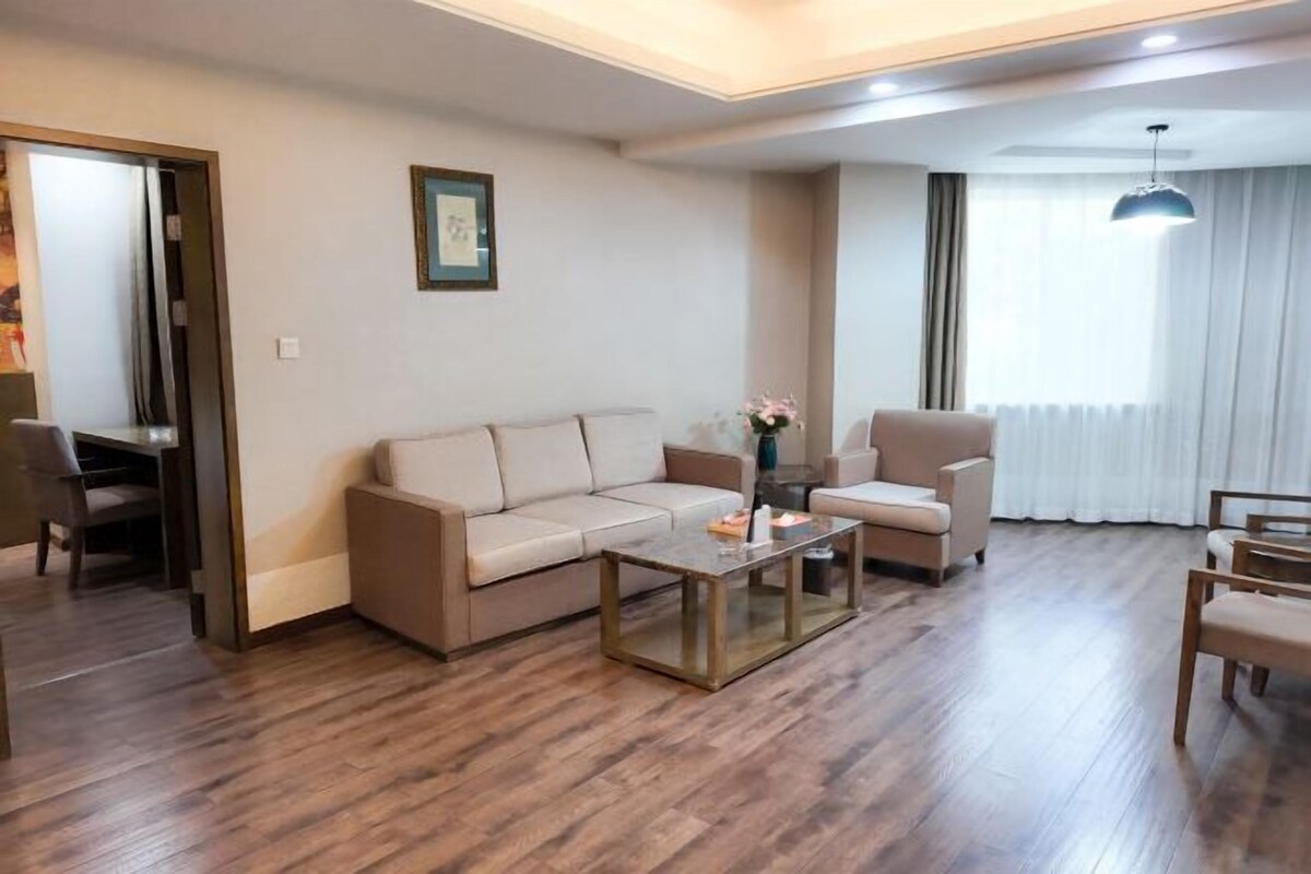 A modern living room with a sofa, armchair, coffee table, and a dining area with chairs.