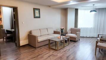 A modern living room with a sofa, armchair, coffee table, and a dining area with chairs.
