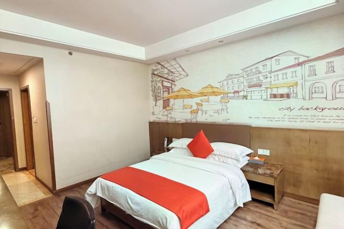 A hotel room with a bed, a nightstand, a wall mural, and a wooden floor.