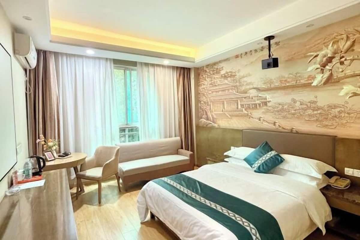 Una habitació d'hotel amb un llit, una taula, una cadira i una finestra amb cortines.