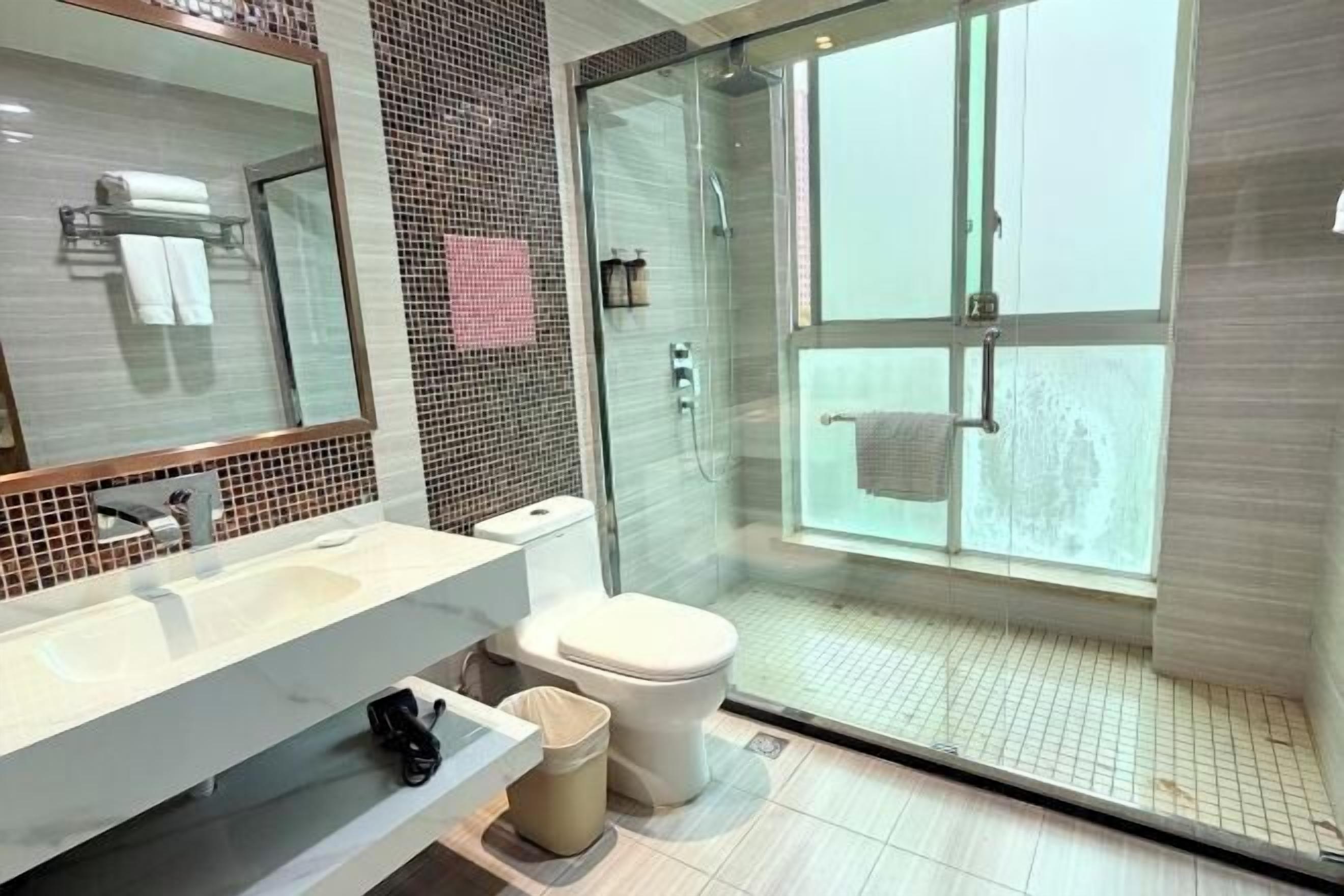 A modern bathroom with a glass shower enclosure, a large mirror, and a white sink.