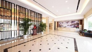 A spacious lobby with a polished marble floor, a reception desk, and a decorative wall with vertical slats. - Mango City Inn (Moon Lake Park North Metro · Window of the World Mango Pavilion) (Changsha)