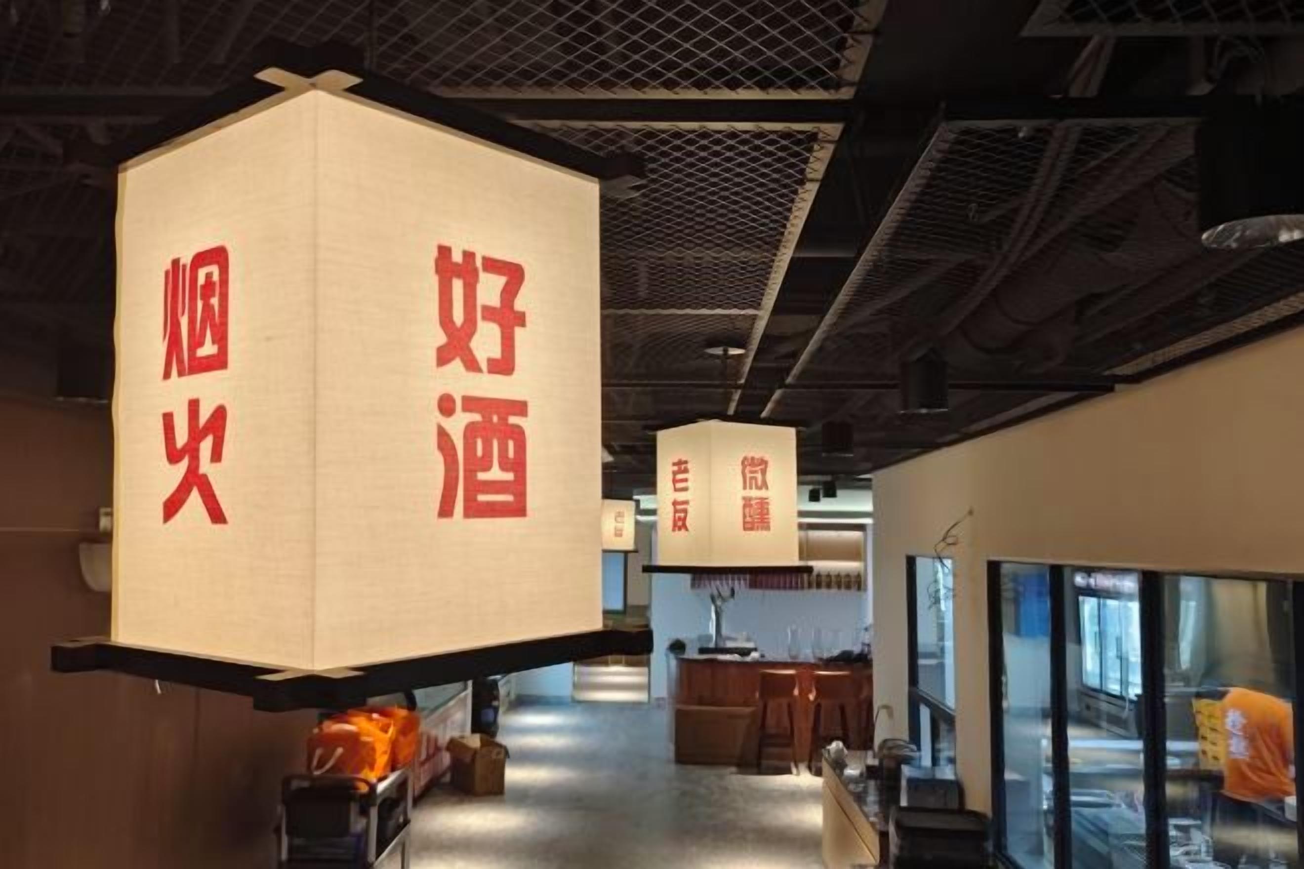 Un couloir orné de lanternes suspendues sur lesquelles figurent des caractères chinois, un espace d’accueil avec un comptoir et un grand aquarium.