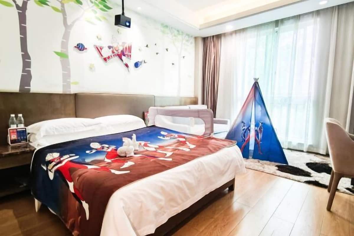 Habitació d'hotel amb un llit, una cadira, una estructura semblant a una tenda i una paret amb un mural d'un arbre.