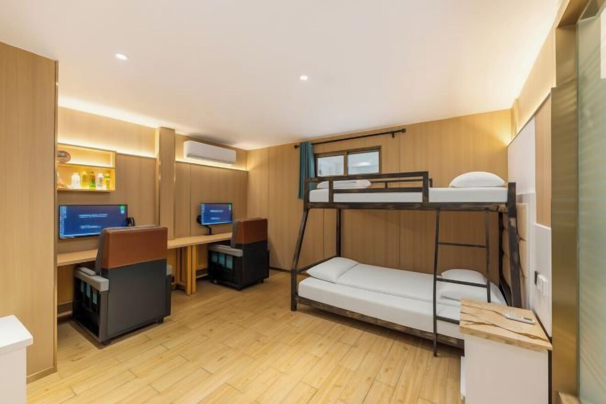 A compact room with bunk beds, a desk with a computer, and a small kitchenette.