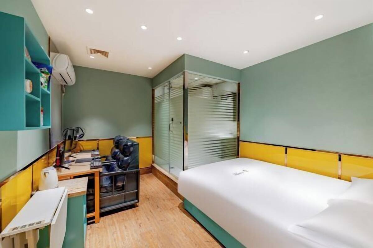 A compact hotel room with a bed, a desk, and a small kitchenette.
