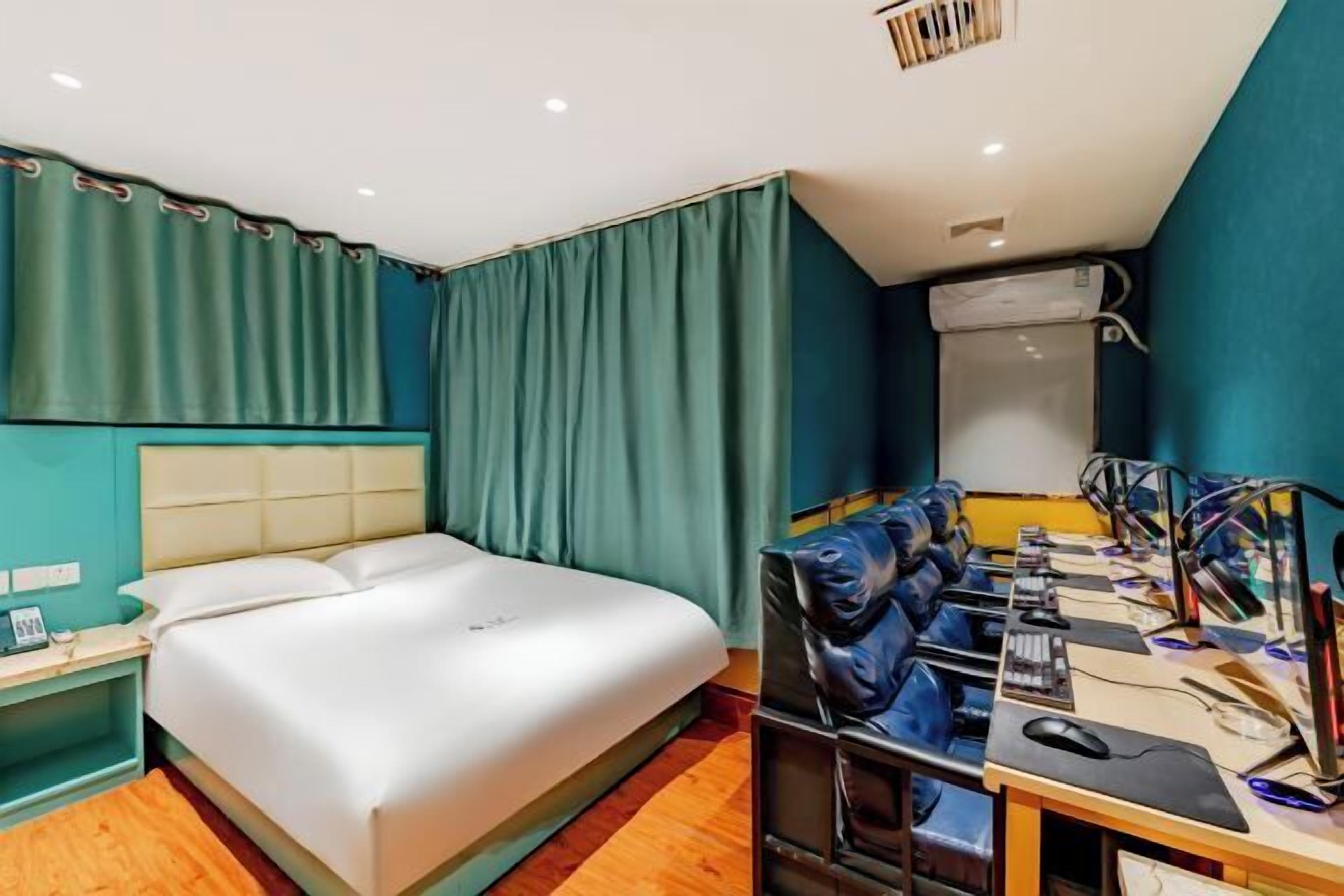 Een hotelkamer met een bed, een bureau met een computer en een spiegel.