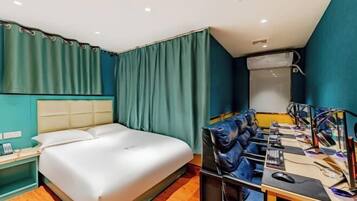 Een hotelkamer met een bed, een bureau met een computer en een spiegel.