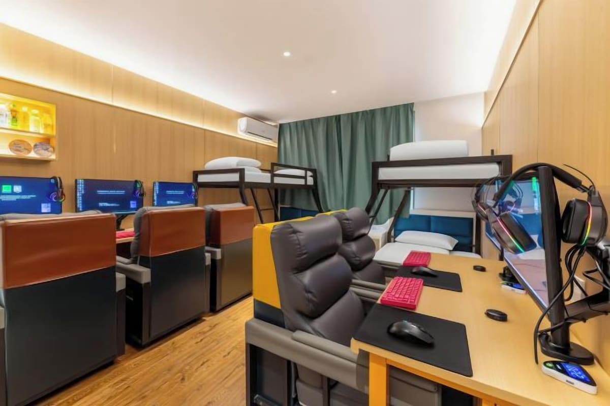 A hotel room with a bunk bed, a desk with a computer, and a seating area with chairs.