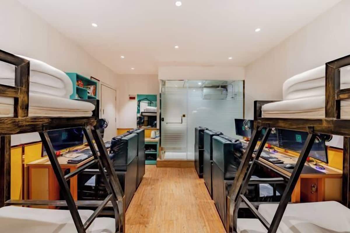 A room with bunk beds, desks, and chairs, suggesting a dormitory or shared accommodation setting.