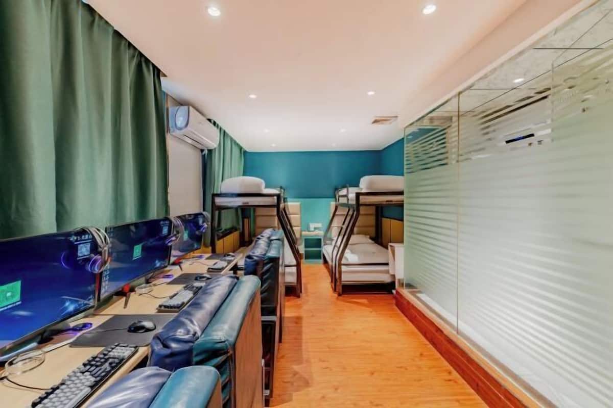 A room with bunk beds, a desk with a computer, and a window with blinds.