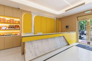 A reception area with a marble counter, yellow walls, and a view of parked cars outside. - Feiyu Network Hotel (Huainan Rome Square Store) (Huainan)