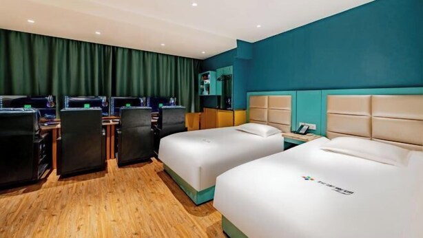 Habitación de hotel con dos camas, un escritorio, sillas y un minibar.