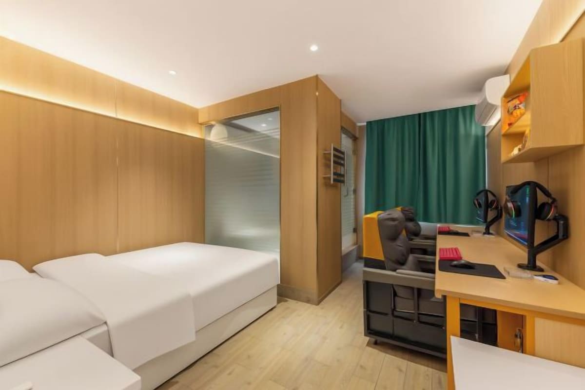 A hotel room with a bed, a desk, a chair, and a wardrobe.
