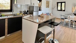 A modern kitchen with a central island, built-in appliances, and a dining area with a glass table and chairs.