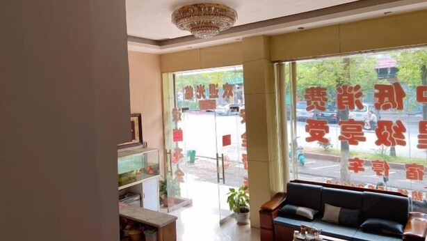 A hotel lobby with a reception desk, seating area, and large windows with signage. - Hakka Hotel (Huichang)