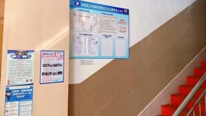A staircase with red steps and a handrail, flanked by informational posters on a wall. - Hakka Hotel (Huichang)