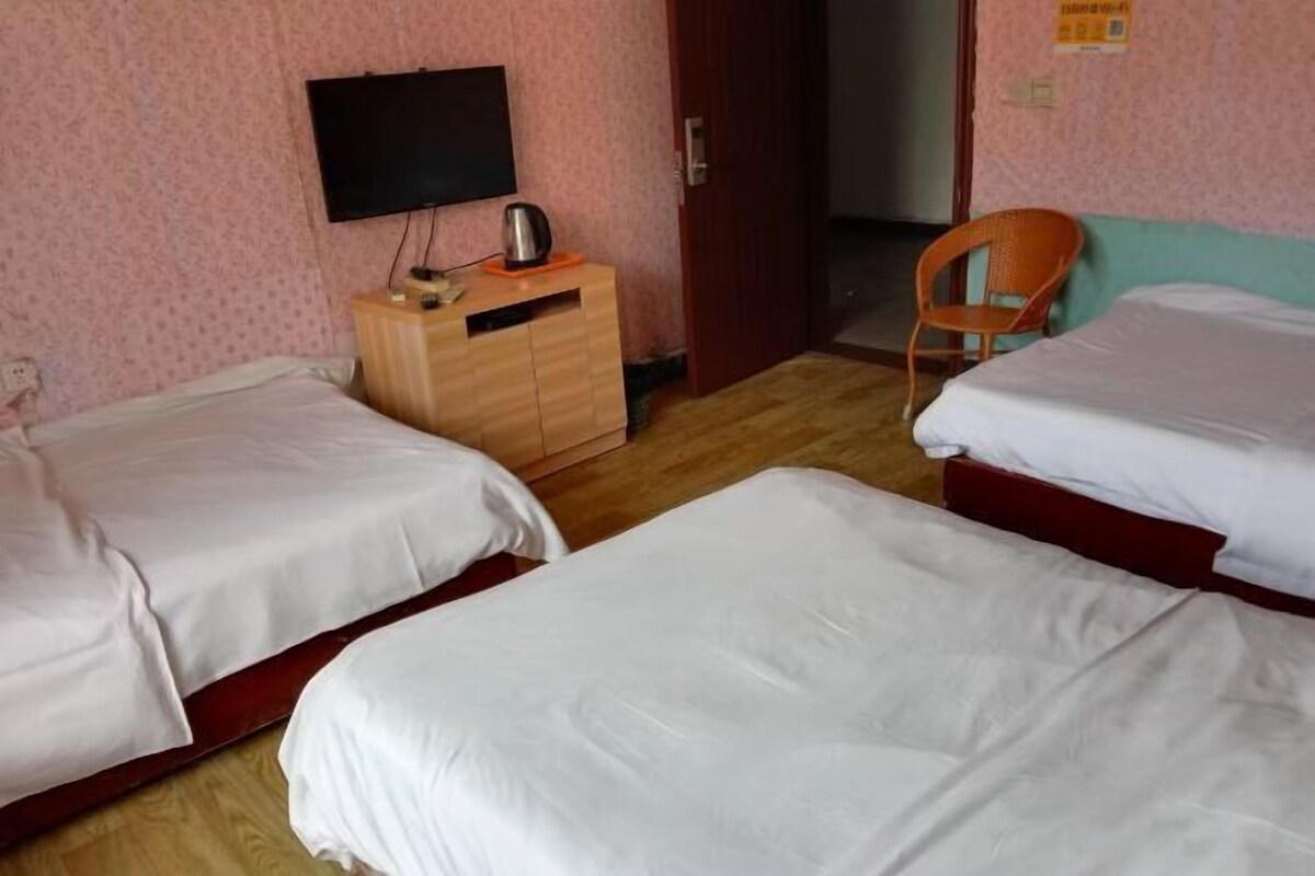 A room with two beds, a wooden dresser, a television, and a chair.