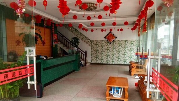 Un espace d’accueil avec un comptoir vert, des sièges en bois et des lanternes rouges.