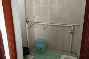 Un baño pequeño con un inodoro, un cubo azul y un pasamanos.