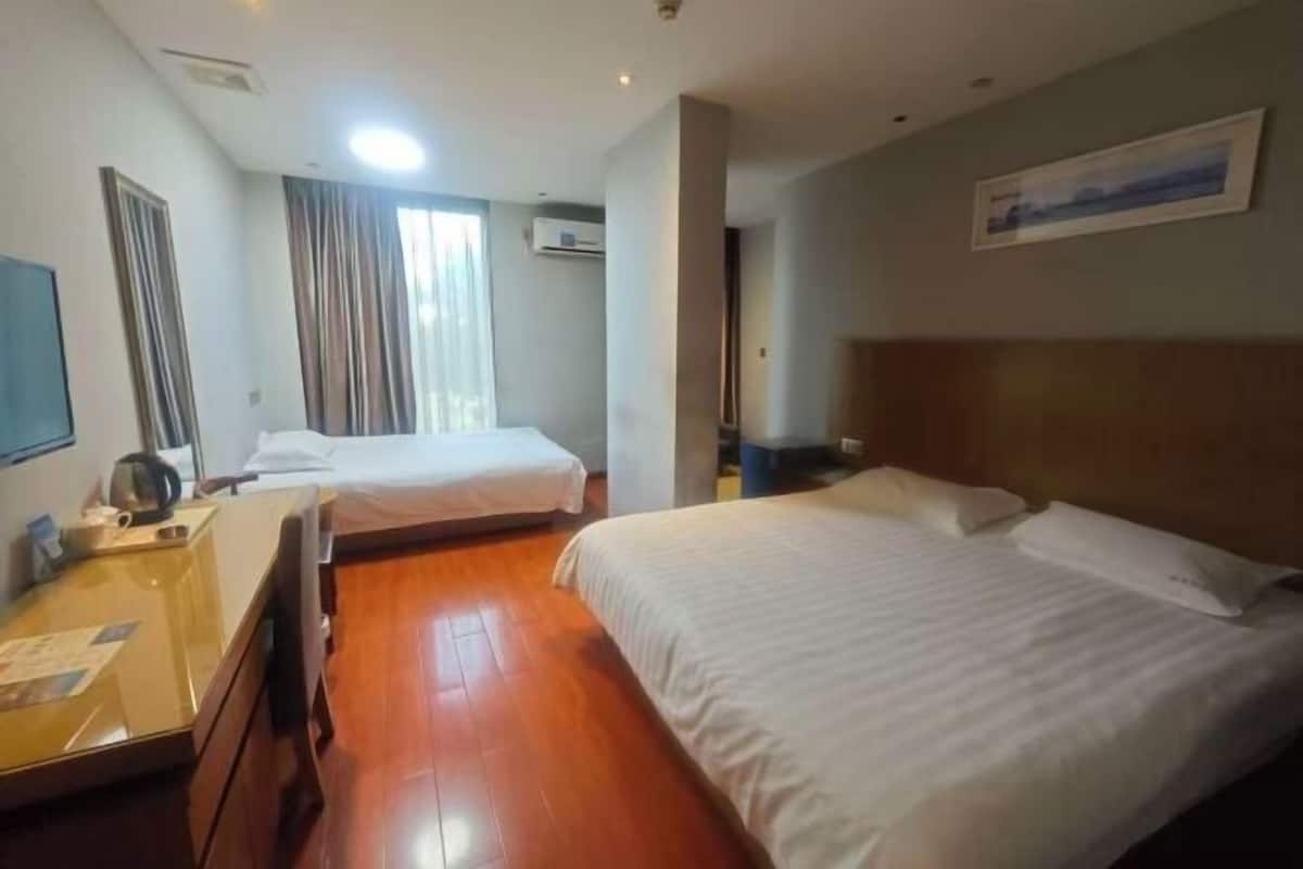 A hotel room with two beds, a desk, a chair, and a television.