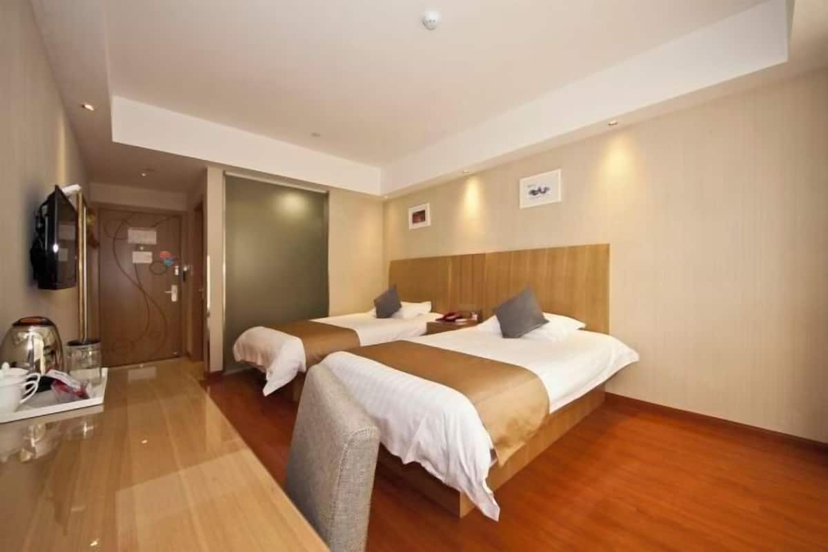 A hotel room with two beds, a wooden headboard, a flat-screen TV, and a small table with a tray.