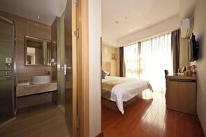 A hotel room with a large bed, a bedside table, a mirror, and a bathroom with a sink and shower. - Ruisi Hotel (Wenzhou College East Road Branch) (Wenzhou)