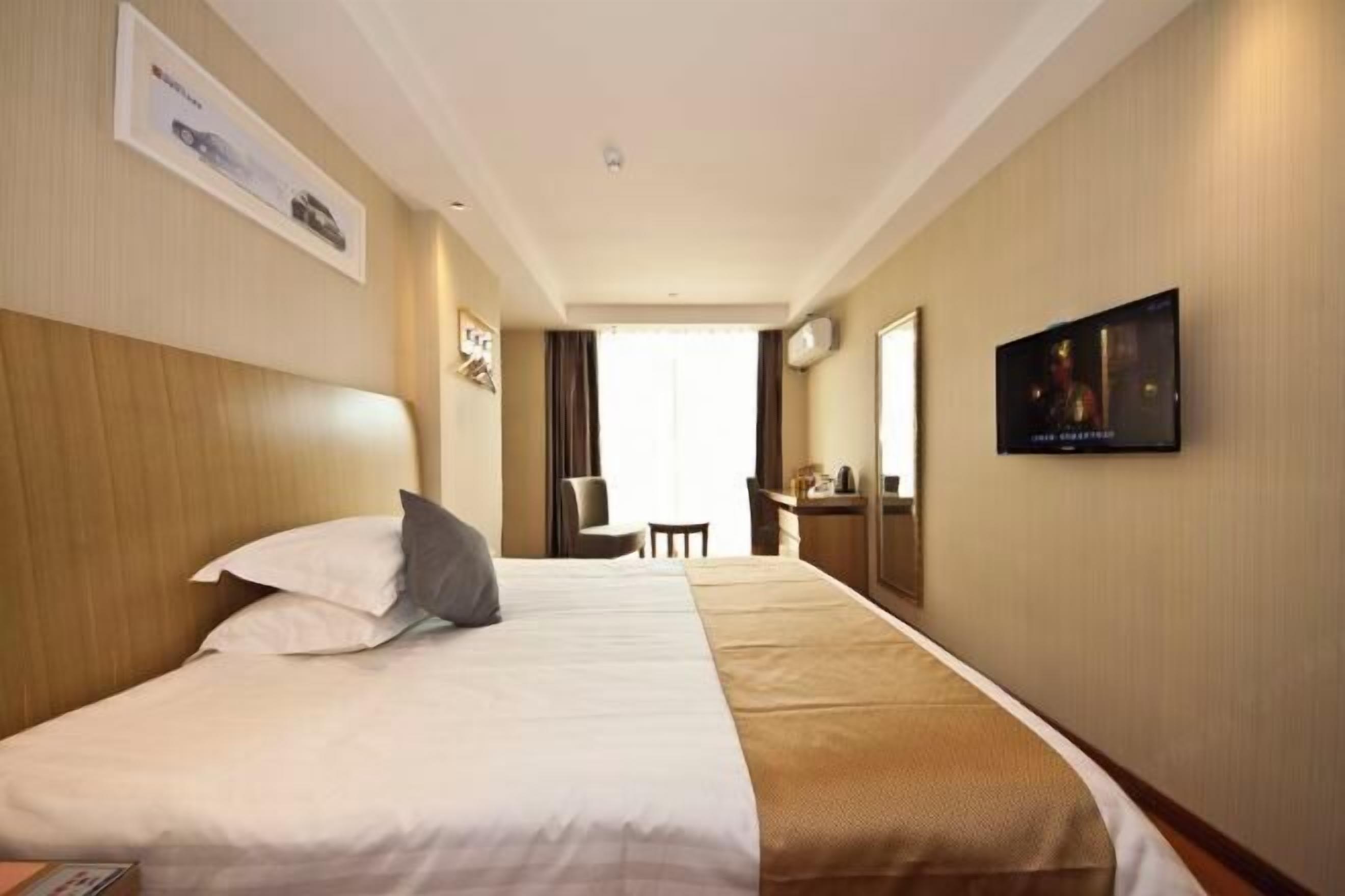 A hotel room with a large bed, a television, and a desk with a chair.