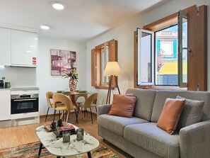 Ein modernes Wohnzimmer mit grauem Sofa, einem Couchtisch und einem Essbereich mit Stühlen und Tisch.