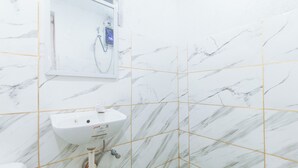 Un baño con un lavamanos blanco, un espejo y una ducha con pantalla digital.