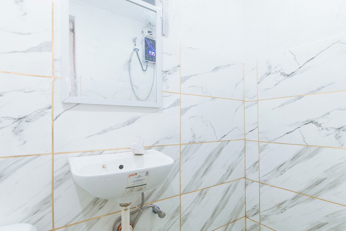 Un baño con un lavamanos blanco, un espejo y una ducha con pantalla digital.